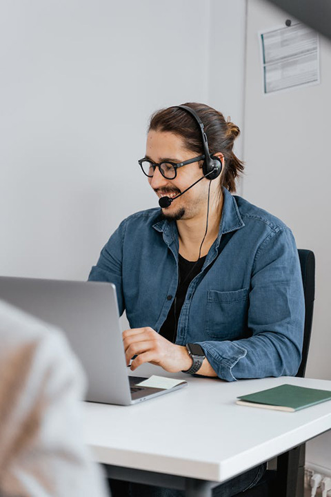 man-with-black-headset-and-mouthpiece-sitting-at-table